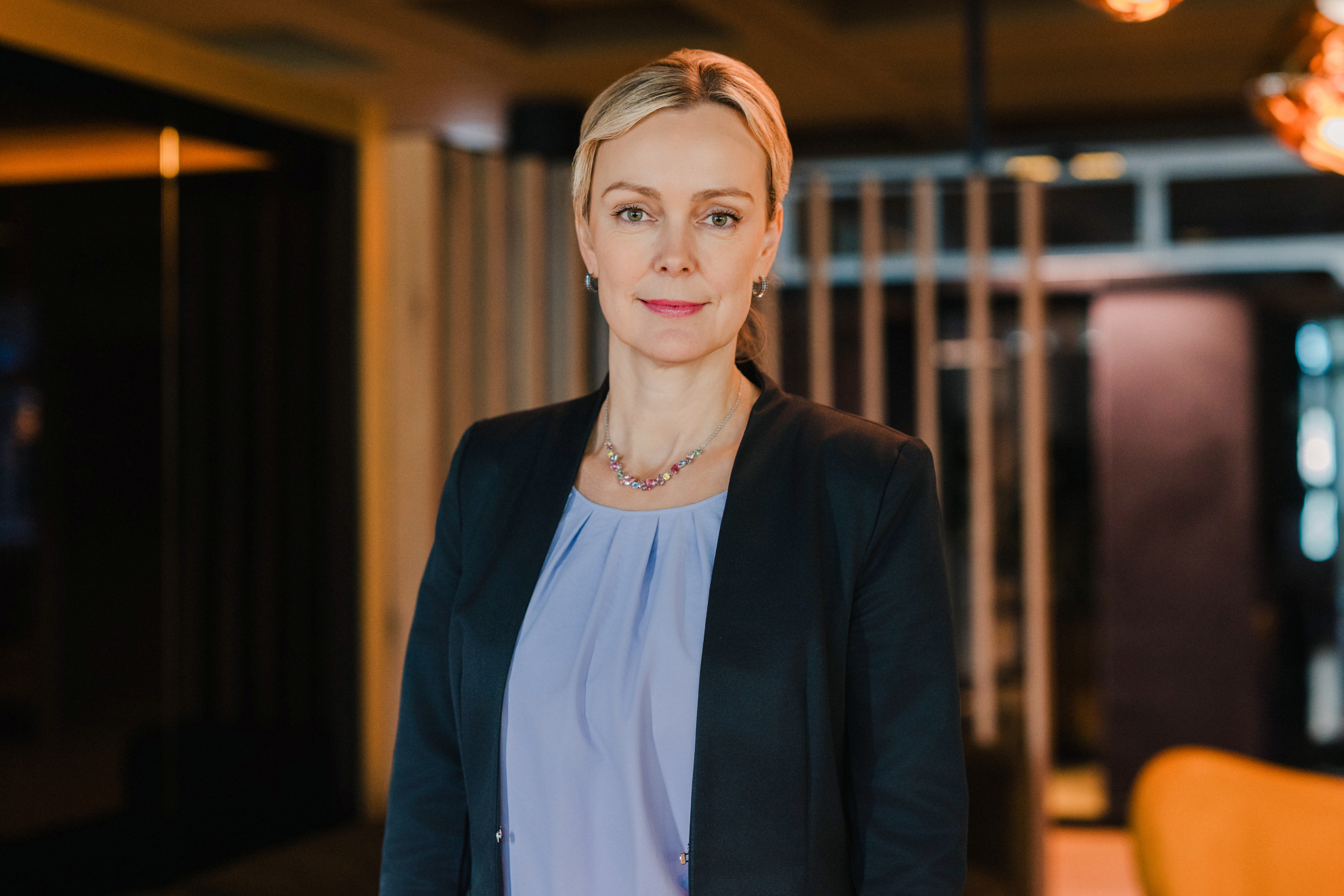 IHK-Geschäftsführerin Manja Schreiner im Portrait. Hinter ihr ein Holzstangenkonstrukt einer modernen Lobby.