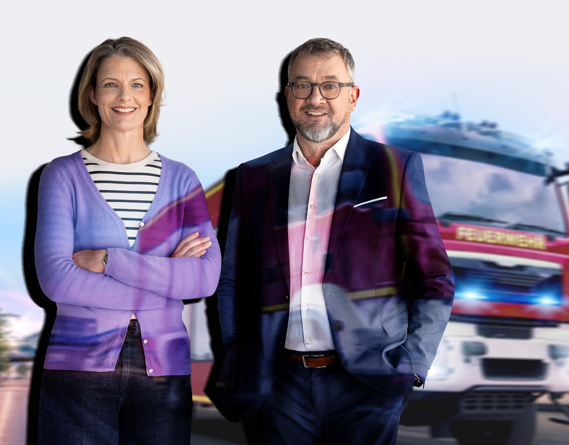 Das berlinovo-Geschäftsführungsduo Caroline Oelmann und Alf Aleithe beim Pressegespräch. Auf beide sowie auf die Wand dahinter wird das Foto eines Feuerwehrautos projiziert.