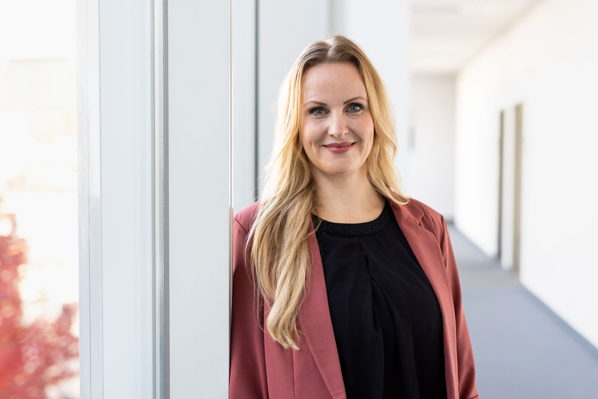 Portraitfoto von Frau Dr. Sindermann, Abteilungsleiterin Personalentwicklung & Kultur bei der Stromnetz Berlin GmbH , die an der Wand eines Büroflurs lehnt.